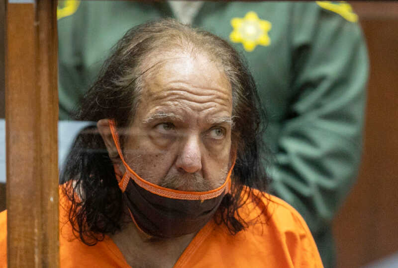 Ron Jeremy sitting in prison uniform