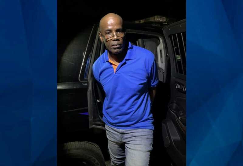handcuffed suspect Michael Douglas in blue shirt