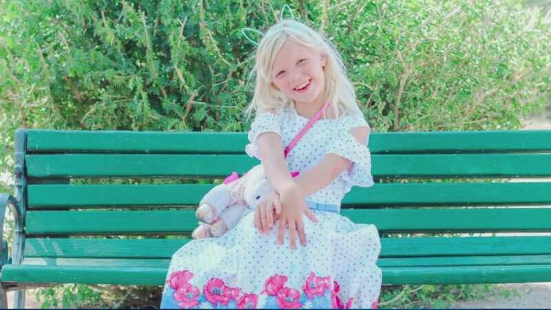 Rebekah Baptiste in white dress on green bench