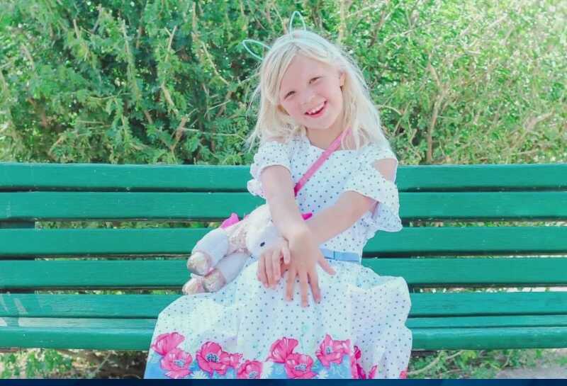 Rebekah Baptiste in white dress on green bench